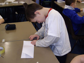 Making the first fold on a paper aeroplane.