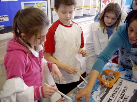 These children are sticking clouds shapes at the top of the collage on the section of blue tissue-paper sky.