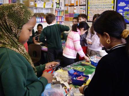 These children are cutting up shiny stickers to add to the border. The collage also had glitter stuck to it.